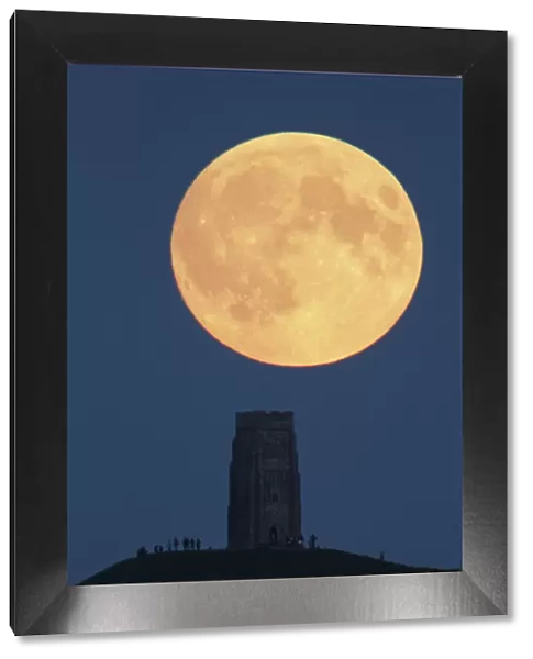 Super moon rising above Glastonbury Tor with people watching, Somerset, England, UK
