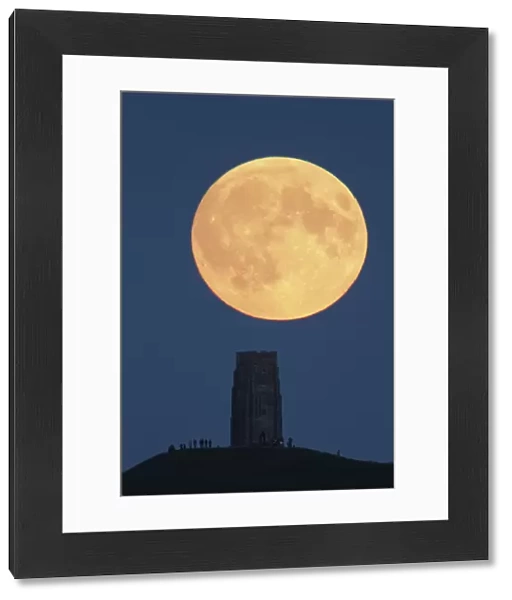 Super moon rising above Glastonbury Tor with people watching, Somerset, England, UK