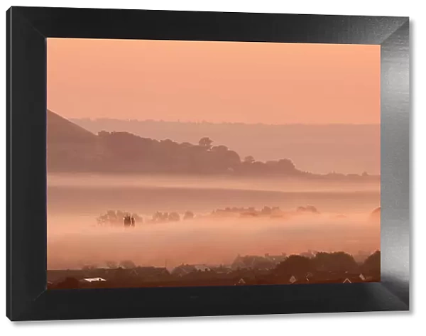 View towards Glastonbury Tor with low lying mist at sunrise from Waltons Hill, Glastonbury, Somerset, UK, August 2013
