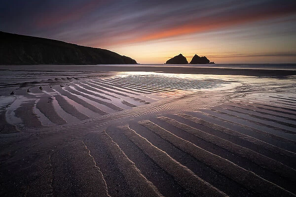 Holywell Bay at low tide, ripples and reflections at sunset, looking towards Carter's Rocks, Holywell Bay, near Newquay, Cornwall, UK. March 2021