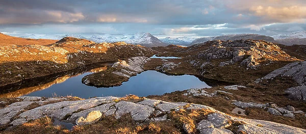 Remote hill lochan with view towards Loch Torridon and Ben Damph, in late winter light, Wester Ross, Scotland, UK, March 2017