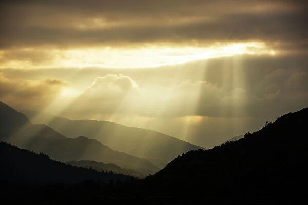 Shafts of light at dusk over Wrynose pass and the Coniston hills from Ambleside, Lake District
