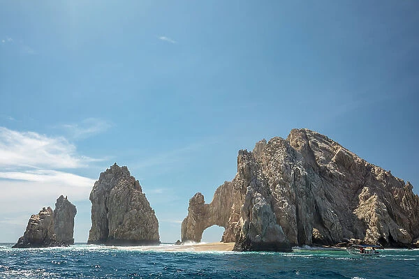 Tourist boat passing the arch of Cabo San Lucas, a distinctive granitic rock formation at the southern tip of Cabo San Lucas, Baja California, Mexico, Pacific Ocean. October, 2018