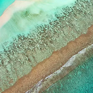 Aerial view of waves breaking on reef edge and sand bank, along South Ari Atoll, Maldives, Indian Ocean. February, 2020