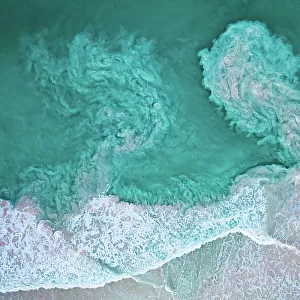 Waves crashing on beach and carrying sediments back out to sea, aerial view. The Bahamas