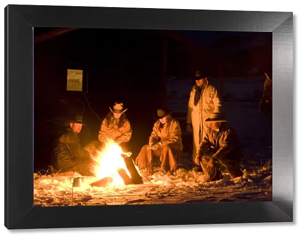 Cowboys sitting round camp fire, Flitner Ranch, Shell, Wyoming, USA Model released