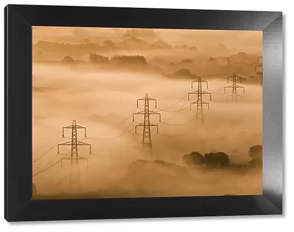 Electricity pylons rising through mist at dawn, view of The Marshwood Vale from Lambert s