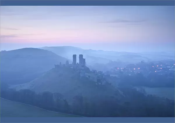 Corfe Castle, sunrise and early morning mist, view from West Hill, Corfe, Dorset, England, UK