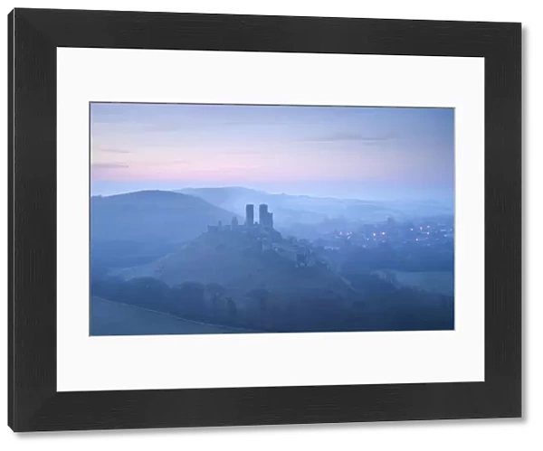 Corfe Castle, sunrise and early morning mist, view from West Hill, Corfe, Dorset, England, UK