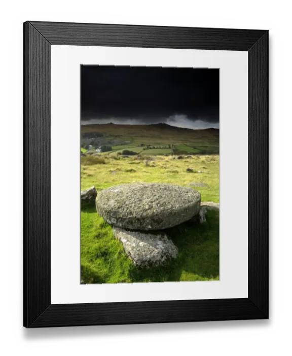 Framed Print : Hut circle remains and large circular granite slab, against stormy sky, Merrivale