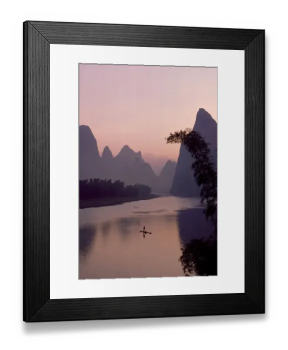 Framed Print : Man using pole to propel bamboo raft on Lijang / Li River, Karst peaks beyond. At dawn Framed Print : Man using pole to propel bamboo raft on Lijang / Li River, Karst peaks beyond. At dawn