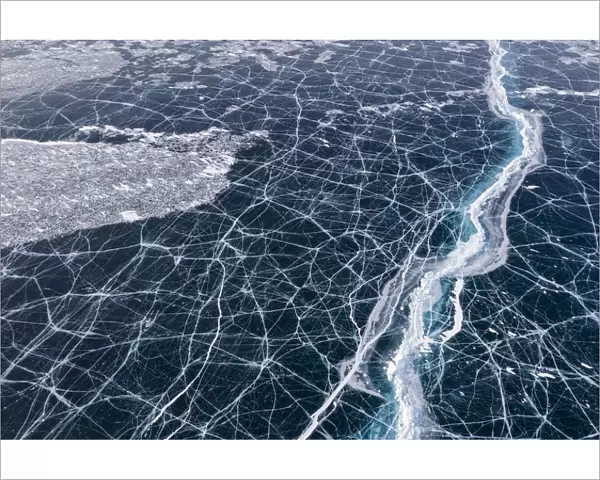 Transparent black ice with cracks on Lake Baikal, aerial shot