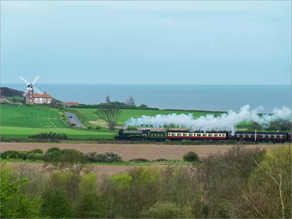 Steam train on the Heritage Poppy Line from Sheringham to Holt, with Weybourne Mill in background