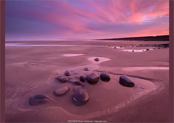 Westward Ho! beach at sunrise, colourful sky at low tide and tidal pool, north Devon, UK