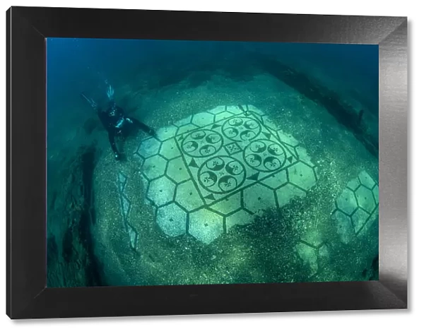 Scuba diver exploring splendid ancient Roman tessellatum mosaic in black and white decorated with pattern of hexagons, perfectly preserved, in Villa a Protiro. Marine Protected Area of Baia, Naples, Italy. Tyrrhenian sea. S