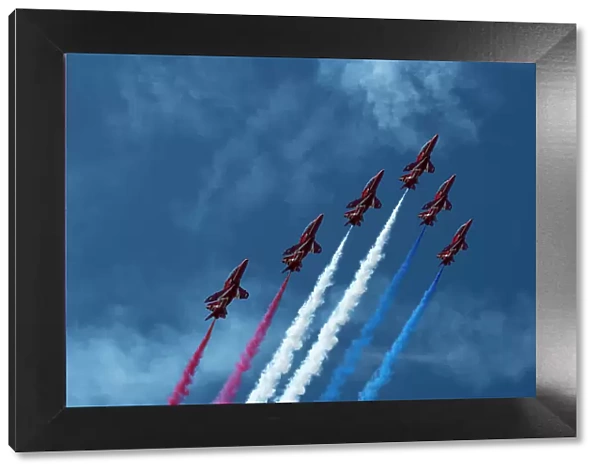 The Royal Air Force Red Arrows display team in formation with red, white and blue contrails, over Rhosneigr, Anglesey, Wales, UK. August, 2022