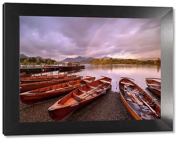 Rowing boats and jetties along the shore of Derwentwater, morning light and rainbow, Keswick, Cumbria, The Lake District, UK. October 2019
