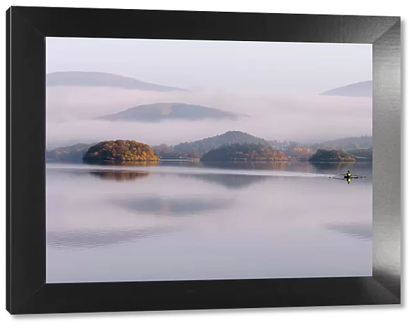 View over Derwentwater, towards Friars Crag in autumn colour and morning mist with lone rower. Near Keswick, The Lake District, Cumbria, UK. November 2016
