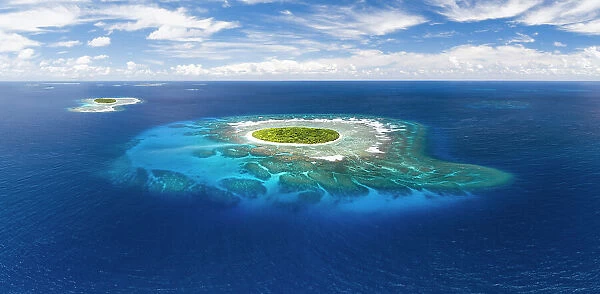 Aerial panorama of Fangasito Island with the underwater coral reef clearly visible, Vava'u island group, Kingdom of Tonga, South Pacific, with Fonua'one'one island visible in the background. September 2019