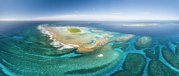 Aerial panorama of Maninita Island which sits atop an extensive coral reef structure, which is for the most part not visible from the surface of the ocean. Visible to the right behind Maninita is Taula Island
