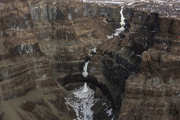 Aerial view of frozen waterfall in deep canyon in plateau, Putoransky State Nature Reserve, Putorana Plateau, Siberia, Russia. May, 2021