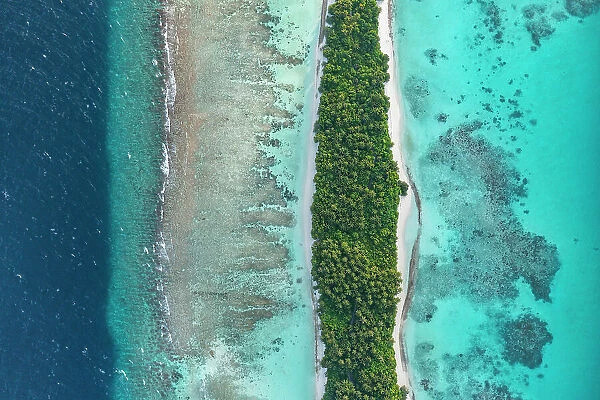 Aerial view of narrow coral atoll island with palm trees and white sand beach surrounded by reef, Dhigurah Island, South Ari Atoll, Maldives, Indian Ocean. February, 2020