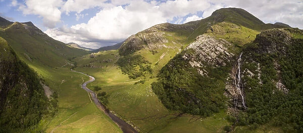 Aerial view of Steall waterfall lined by Birch (Betula pendula) woodland and river running through Glen Nevis, Highlands, Scotland, UK. June, 2018