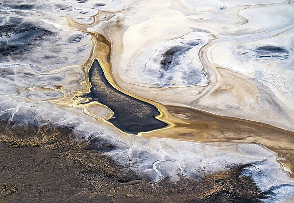 Aerial view after sunrise, showing the sun reflecting off water that has flowed into Lake Eyre South and formed a pond; the water being the result of recent uncommonly high local desert rainfall