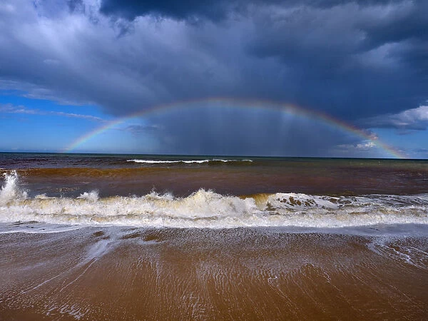 Autumn high tides with stormy skies and rainbow over the sea, Walcott, Norfolk, England