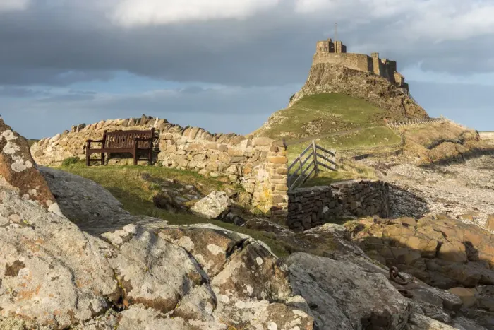 Framed Print : Bench in front of a wall with Lindisfarne Castle in the distance, Holy Island, Northumberland Framed Print : Bench in front of a wall with Lindisfarne Castle in the distance, Holy Island, Northumberland