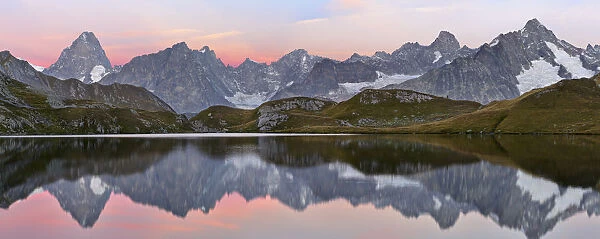 Colourful pink sky at dawn reflected in Fenetre Lake  /  Lac de Fenetre in Swiss Alps, 2456 m above sea level. Mont Blanc, Grande Jorasses, Aiguille du Talefre, Aiguille du Triolet and Mont Dolent in Ferret Valley (Val Ferret) beyond