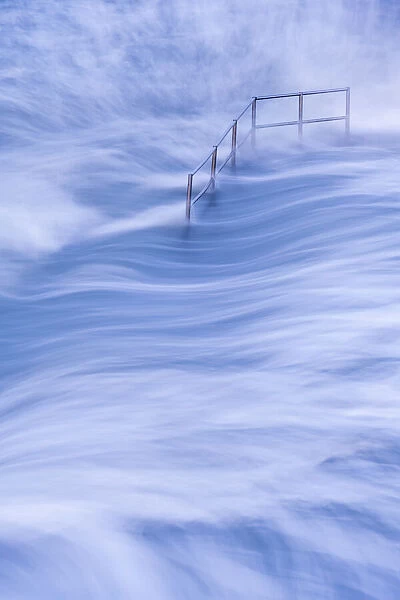 High tide and metal hand railings at Bude Sea Pool, Bude, North Cornwall, UK. May 2021