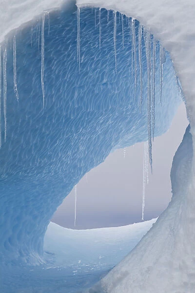 A large hole in an iceberg with icicles hanging. Yalour Islands, Antarctic Peninsula