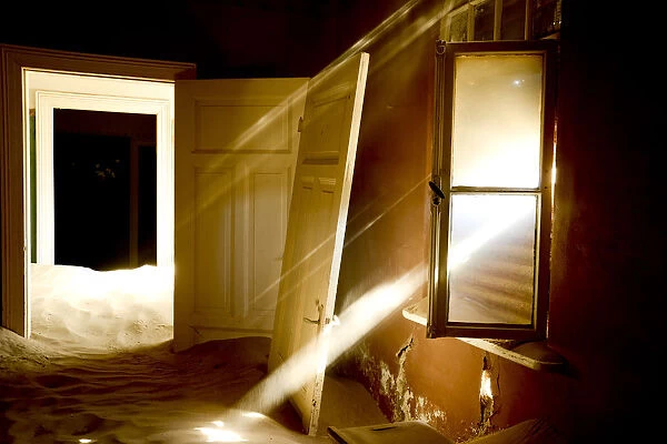 Light streaming through window on sand covered house in Kolmanskop Ghost Town, an