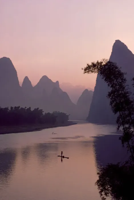 Framed Print : Man using pole to propel bamboo raft on Lijang / Li River, Karst peaks beyond. At dawn Framed Print : Man using pole to propel bamboo raft on Lijang / Li River, Karst peaks beyond. At dawn
