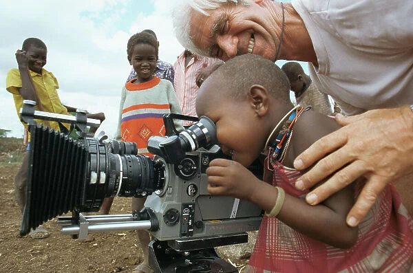 Masai child looking through film camera lens with cameraman Alan Hayward, on location for BBC series Lifesense, Kenya, East Africa 1991