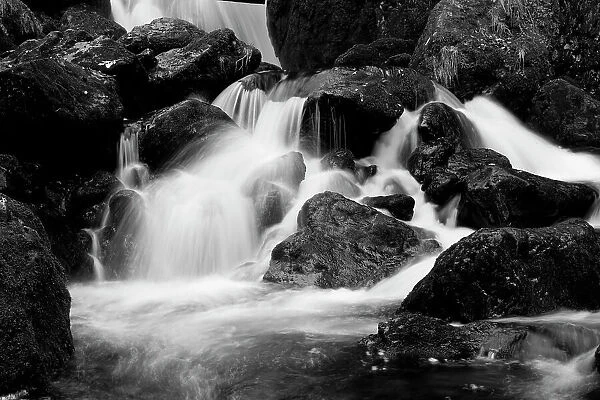 Monochrome image of waterfall breaking on rocks at the base of Lodore Falls, Lake District NP, Cumbria, England, UK, November