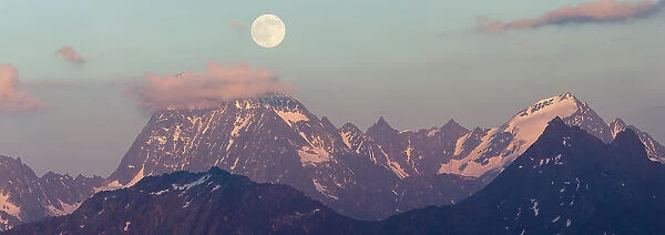 Full moon rising over the Watzespitze (3554m), part of the Glockturmkamm, the westernmost ridge of the Otztal Alps. Nordtirol, Austrian Alps. July. Digitally stitched panorama