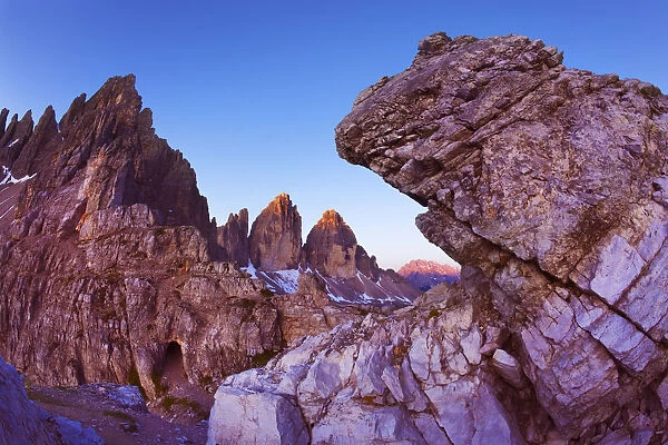 Paternkofel (left) and Tre Cime di Lavaredo mountains at dawn seen behind rocks, Sexten Dolomites