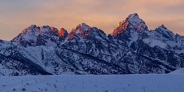 The last rays of sunset hit the Grand Teton and adjacent peaks on a winter evening. Grand Teton National Park, Wyoming, USA