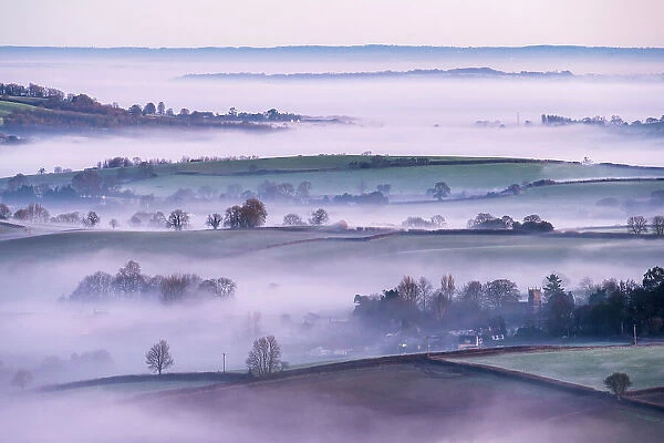 RF - Frosty and misty winter sunrise from Pilsdon Pen, looking across Marshwood Vale. Dorset, UK. January. (This image may be licensed either as rights managed or royalty free)