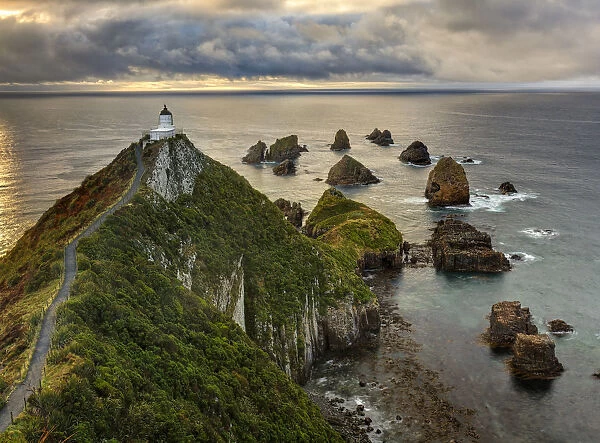 RF- Nugget Point (Ka Tokata) lighthouse at sunrise, rain clouds sweeping in from the horizon