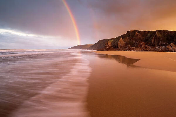 RF - Sandymouth Bay, early morning light and rainbow at low tide, north Cornwall, UK. December 2020. (This image may be licensed either as rights managed or royalty free.)