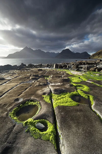 Rocky shoreline, Loch Scavaig and view to Cuillin mountians, Isle of Skye, Scotland, UK, April