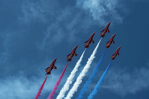 The Royal Air Force Red Arrows display team in formation with red, white and blue contrails, over Rhosneigr, Anglesey, Wales, UK. August, 2022