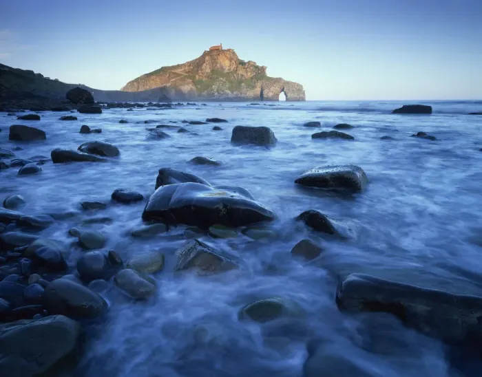 Framed Print : Sea over smooth rocks with rock arch in distance, Gaztelugatxe coast, Basque country
