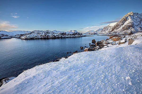 Snow over shore and mountains in winter, Henningvaer, Lofoten Islands, Norway. March, 2023