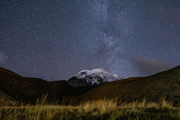 Snowcapped peak of Chimborazo volcano at night with part of the Milkyway visible in sky above, Chimborazo National Park, Chimborazo, Ecuador. August, 2022