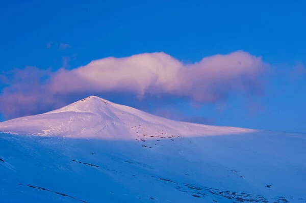 A snowy mountain peak lit by low crepuscular light before sunset. Ordesa National Park