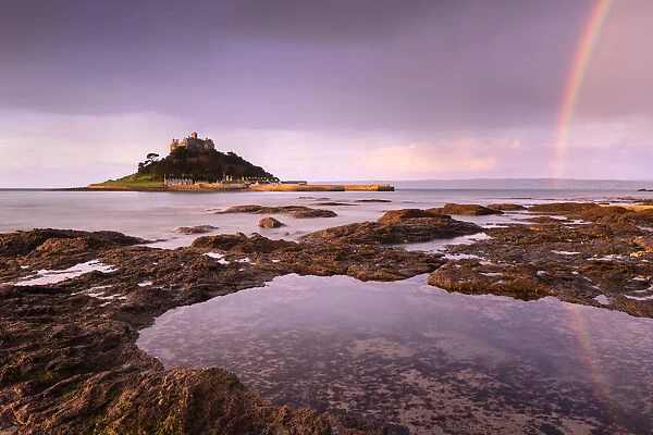 St Michael's Mount at sunrise with a rainbow over Penzance, viewed from Marazion, West Cornwall, UK. February 2019